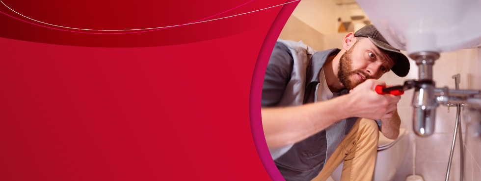 Imagem de fundo vermelho radiante com profissional encanador ajustando o sifão da pia