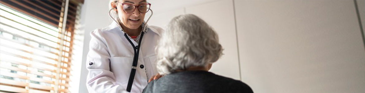 Médica examinando paciente idosa com estetoscópio.