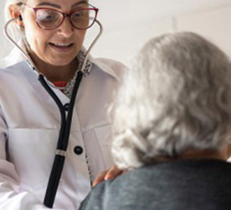 Médica examinando paciente idosa com estetoscópio.