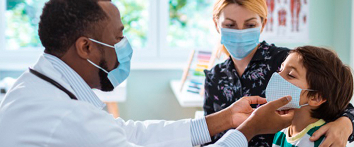Médico pediatra examinando um garoto acompanhado de sua mãe.