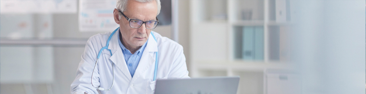 Médico de meia-idade com estetoscópio azul olhando o computador.